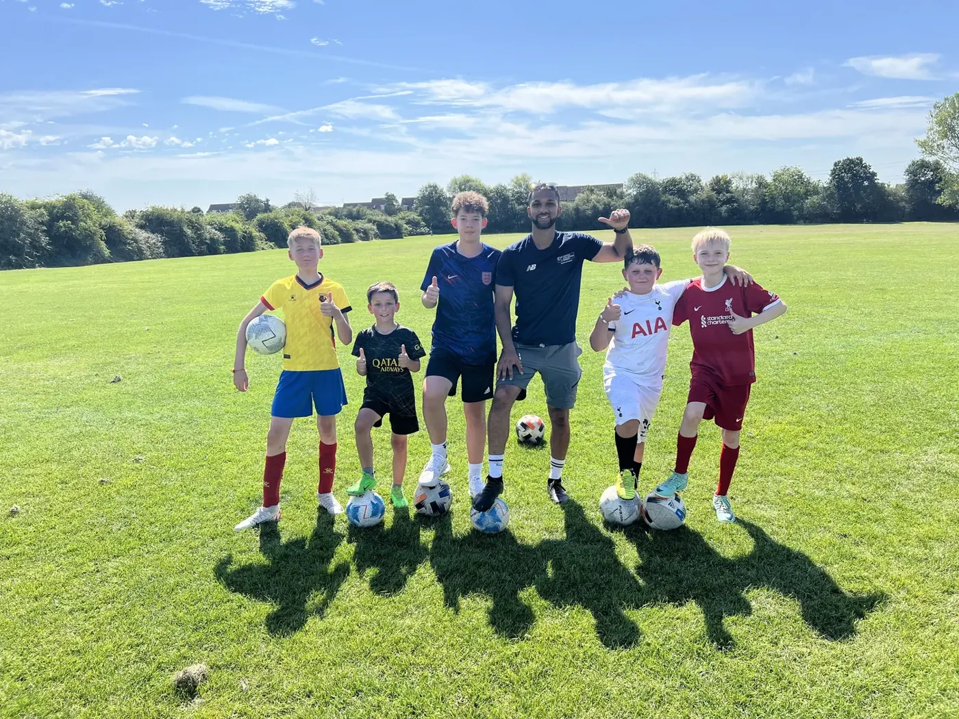 Group of young players with their coach on a sunny pitch